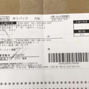 Shipping label on brown cardboard with Japanese text, a barcode, and delivery address fields visible on the right side as the package label.