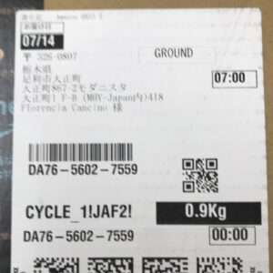 Close-up of a white parcel label showing Ground shipping, 0.9 Kg, a barcode, QR code, and time stamps (07:00 / 00:00).