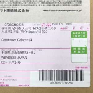 A Japanese shipping label on a cardboard box showing recipient name 'Constanza Galarce', sender details, and a large barcode at the bottom.