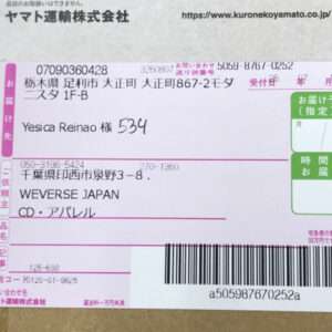 Close-up of a Japanese shipping label on a cardboard box, showing recipient Yesica Reinao, postal codes, and a large barcode with delivery details.