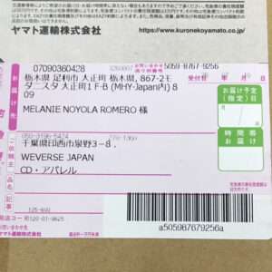 Shipping label on a cardboard box showing recipient 'MELANIE NOYOLA ROMERO' and sender 'WEVERSE JAPAN', with a barcode visible to the right.