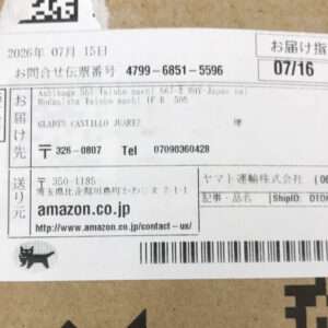 Shipping label on a cardboard box showing recipient name, address, barcodes, and the amazon.co.jp sender info in Japanese and English fonts.