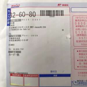 Shipping label from Japan Post with a large barcode, recipient address, and order details visible on the form.