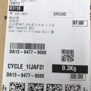 Shipping label showing destination GROUND, 0.3 kg, 07:00, barcode DA13-9477-9080 and a QR code, with Cycle_1JAF2! and a Japanese address.