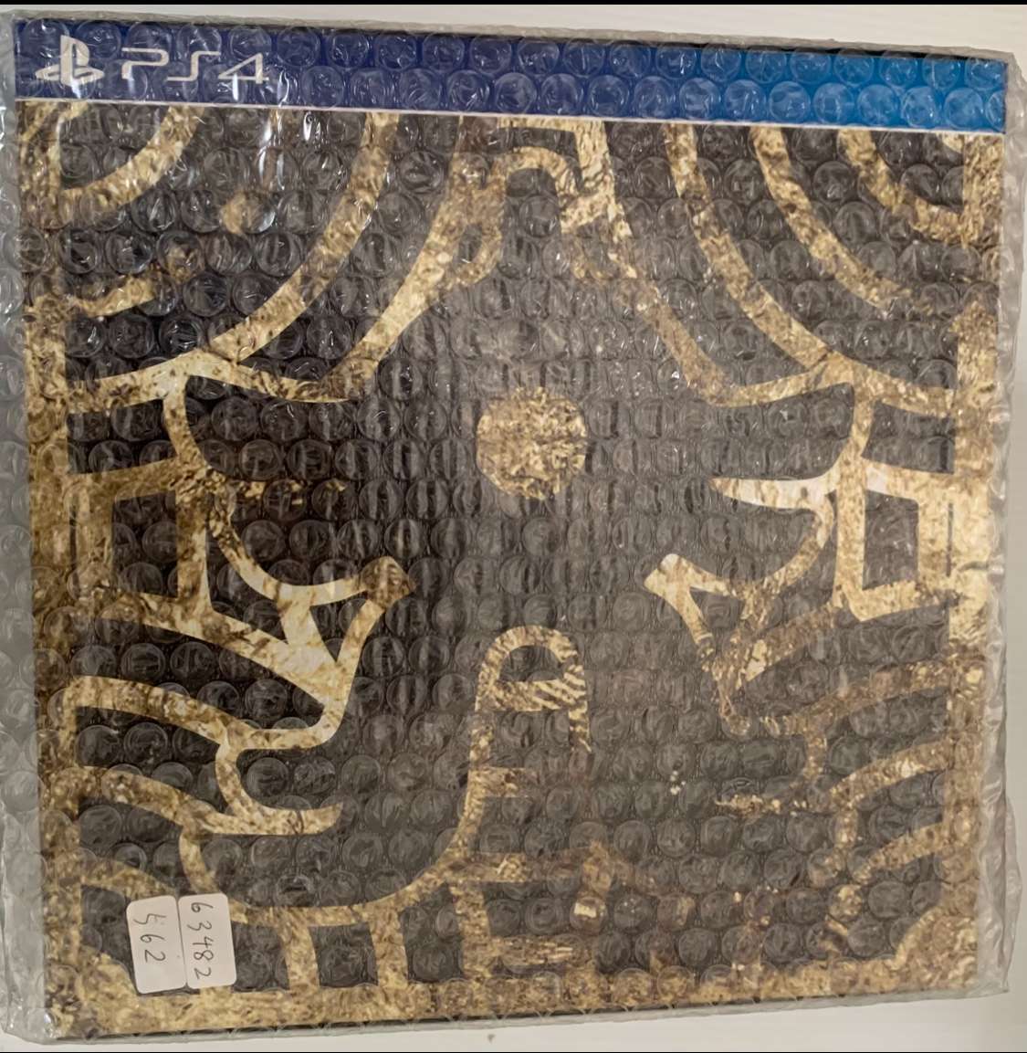 Img_2564 - Articulos Japan (post Box Japan) PS4 game case wrapped in bubble wrap, featuring gold artwork on a dark background and a blue PS4 banner at the top Articulos Japan (Post Box Japan)