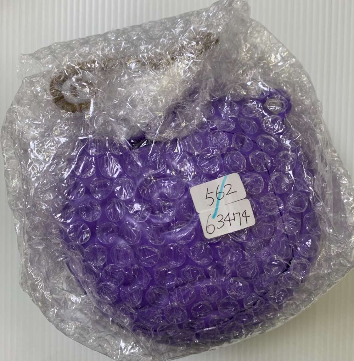 Img_2584 - Articulos Japan (post Box Japan) Bag of purple plastic caps wrapped in bubble wrap with a white label showing numbers (562, 63474). Articulos Japan (Post Box Japan)