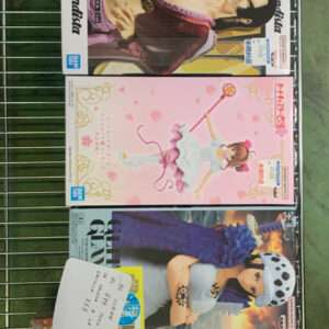 Shelf of anime figure boxes on a metal rack, varied box art and character designs visible in a store display collection.