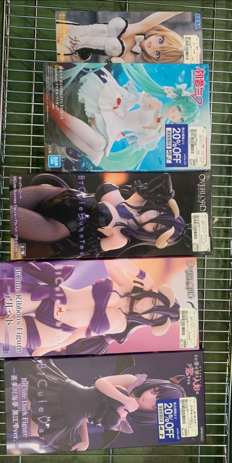 Img_2605 - Articulos Japan (post Box Japan) Row of anime figure boxes on a metal shelf, each showing stylized female characters in fantasy outfits. Articulos Japan (Post Box Japan)