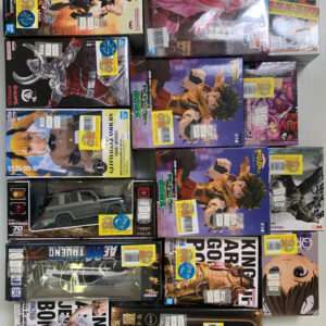 Collection of boxed anime figures and model kits stacked on a shelf, with colorful character art on packaging.