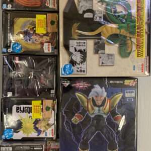 Assorted boxed anime figures and a pink pillow on a light surface, including Dragon Ball Z boxes and manga-themed packaging.  Articulos Japan (Post Box Japan)