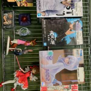 Wire display rack with anime figurines and Japanese manga magazines, showing colorful character figures around boxed comics.