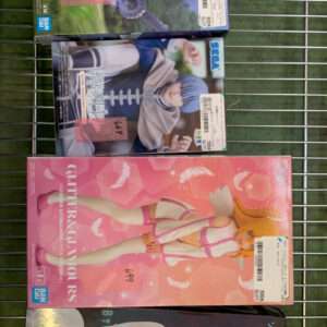 Four boxed anime figures on a metal display rack, each with price stickers and barcode labels visible.