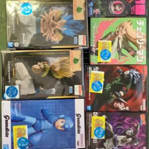 A grid of Dragon Ball Grandista action figure boxes arranged on a green surface, featuring characters like Goku and Vegeta in colorful packaging.