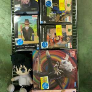 Boxes of anime action figures on a metal rack, with a plush chibi character at the bottom left corner.
