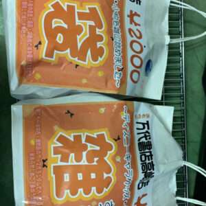 Two orange Japanese snack bags inside a white tote, resting in a metal shopping cart/basket.