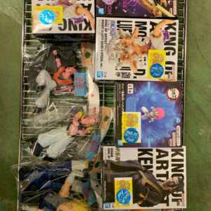 Metal shelving rack on a green floor holding multiple boxed anime figures and several loose figures in plastic bags; boxes feature bold graphics and character art (Dragon Ball/One Piece style).