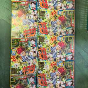 Row of brightly colored manga magazines on a rack, each cover showing a spiky red-haired hero in action with bold Japanese text.