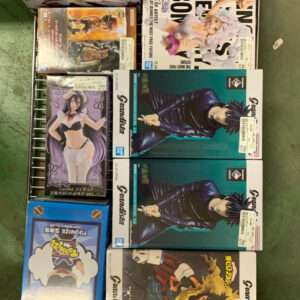 Assorted boxed anime figures on a metal rack, arranged in two columns, featuring colorful packaging and character art. Row of collectible figure boxes on a store shelf, showing various anime characters in dynamic poses from different brands. A selection of boxed figure sets on a wire display rack, including action-figure boxes with illustrated characters. Boxed anime figurines on a shelving unit, stacked and ready for sale, with vibrant cover art and price stickers. Various character figure boxes on a metal rack, showcasing different anime styles and packaging designs.