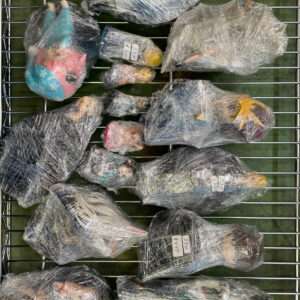 Assorted small items wrapped in plastic on a metal wire rack, with price tags visible on some bundles.
