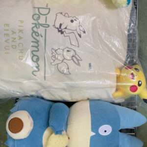 Pile of stuffed animals on a metal rack: a blue dinosaur, a yellow bear-like plush, Pikachu, and a white bag with drawings.
