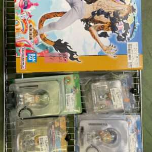 Shelf display of Bandai action figures and model kits; a large orange box with a tiger-like creature artwork dominates, surrounded by smaller blister-pack figures.