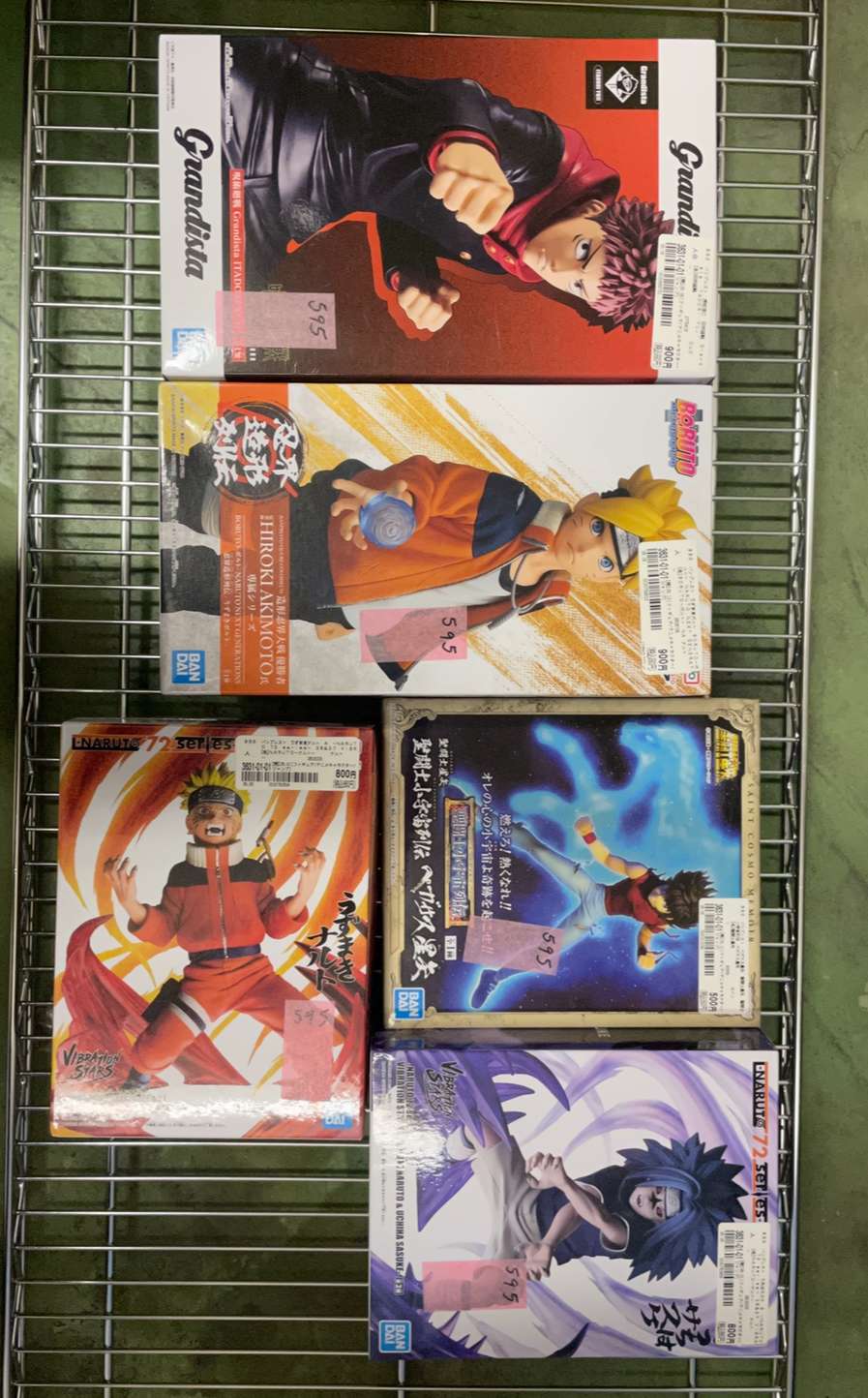 Img_3425 - Articulos Japan (post Box Japan) Six boxed anime figurines on a metal display rack in a store (Naruto and other series). Articulos Japan (Post Box Japan)