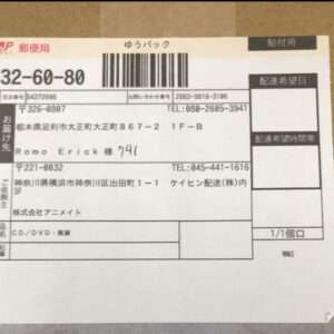 Japanese postal shipping label with a barcode, JP Post logo, and handwritten recipient name on a beige background