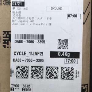 Shipping label on a cardboard box showing destination in Japan, with a large barcode, QR codes, and a weight of 0.4 kg; method 'GROUND' and times like 07:00 and 17:00 visible.