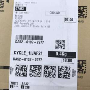 Shipping label on a brown box with barcodes, QR codes, weight 0.4 Kg, destination 'GROUND', times 07:00 and 18:00, and a Japanese recipient/address.