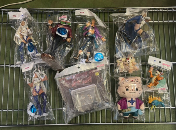 Img_e0732 - Articulos Japan (post Box Japan) Assorted anime action figures and plush toys in clear bags displayed on a metal rack. Articulos Japan (Post Box Japan)