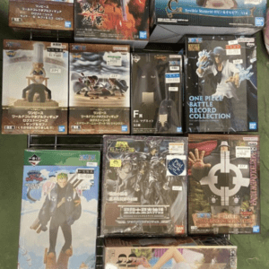Shelf of anime figure boxes showing various characters and scenes in colorful packaging. Includes One Piece, Naruto, and other series figures on a display rack.