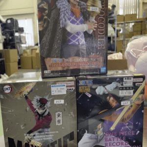 Stack of boxed anime figures on a store shelf, featuring One Piece and other character collectibles