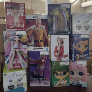 Display of boxed anime figures on a shelf, featuring Qposket and Grandista figures in vibrant packaging forms a stacked storefront.