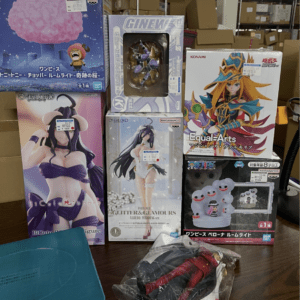 Assorted boxed anime figures on a wooden shelf in a storage area, including Overlord and Konami Equal Arts boxes with colorful character art.
