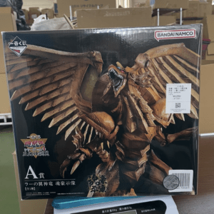 Boxed statue of a large brown winged dragon with an open mouth, Bandai Namco branding visible, on a store shelf poster.