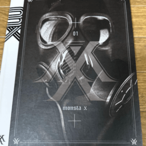 Dark magazine cover with a large Monsta X logo over headphones, bordered corners, and the text 'monsta x'.