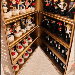 Corner display shelf filled with small anime figurines, white figures on the left and black figures on the right, arranged on multiple tiers around a central corner.