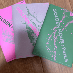 Three colorful magazines titled Golden Hour fanned on a wooden surface (pink, silver, green) with splash artwork on the covers.
