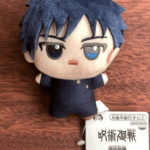 Chibi plush toy of a blue-haired anime character in a dark uniform, lying on a wooden surface with a retail tag visible.