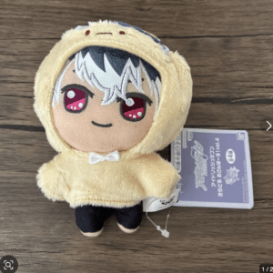 Plush toy in a yellow fluffy hooded outfit with red eyes and white hair, standing on a wooden surface with a tag attached.