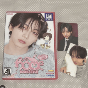 K-pop photo book with a large portrait on the cover and two collectible photo cards beside it on a polka dot surface.