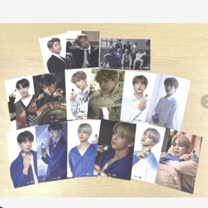 Set of BTS photo cards laid out on a light wood table, arranged in rows and columns.