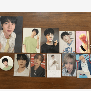 Set of glossy photo cards featuring a young man arranged on a wooden table, plus a round pin with his portrait.