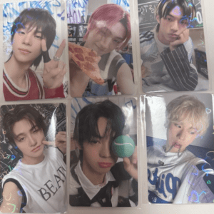 K-pop idol with black hair making a peace sign toward the camera at a photo card. (Top-left)