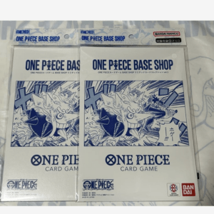 Two packaged One Piece Card Game Base Shop sets side by side, featuring blue manga artwork on white fronts and Bandai branding headlined 'ONE PIECE BASE SHOP'.aiing: