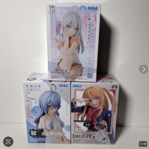 Stack of three SEGA anime figure boxes: lavender-haired figure on top, blue-haired figure bottom left, orange-haired figure bottom right.