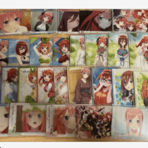 Collection of anime character trading cards featuring pink-haired females in various outfits on a wooden surface.