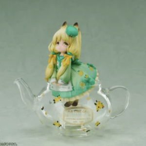 Cute anime-style blonde girl figurine in a green dress perched on a clear glass teapot with yellow flower patterns.