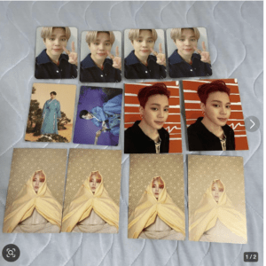 Set of trading cards featuring a young man with blonde hair making peace signs (top) and another portrait series with red hair against orange background (middle). Includes blue-robed figure and two blue/purple cards, plus four yellow-wrap portraits at bottom, all laid on a quilted surface.