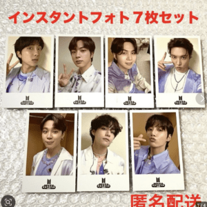 Seven instant polaroid photos of a K-pop group arranged on a textured surface, each with a Festa logo on the bottom.
